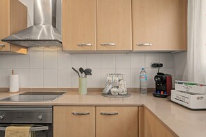 A modern kitchen with wooden cabinets, a stainless steel range hood, a water dispenser, and a coffee maker. - Vacation Home 'La Quinta Adosado' with Sea View, Shared Pool & Wi-Fi (Santa Ursula)