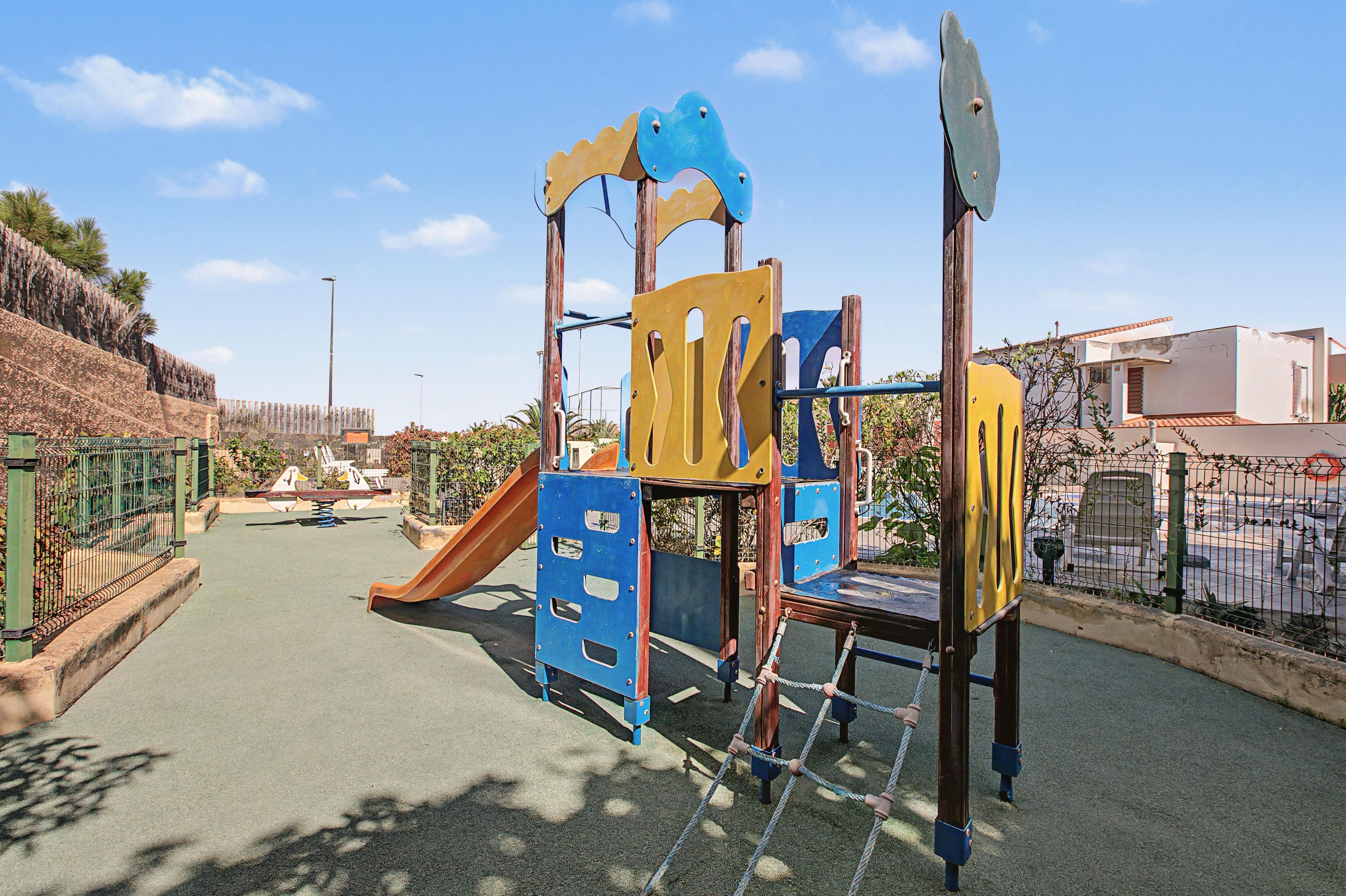 A playground with a slide, climbing structures, and a swing set.