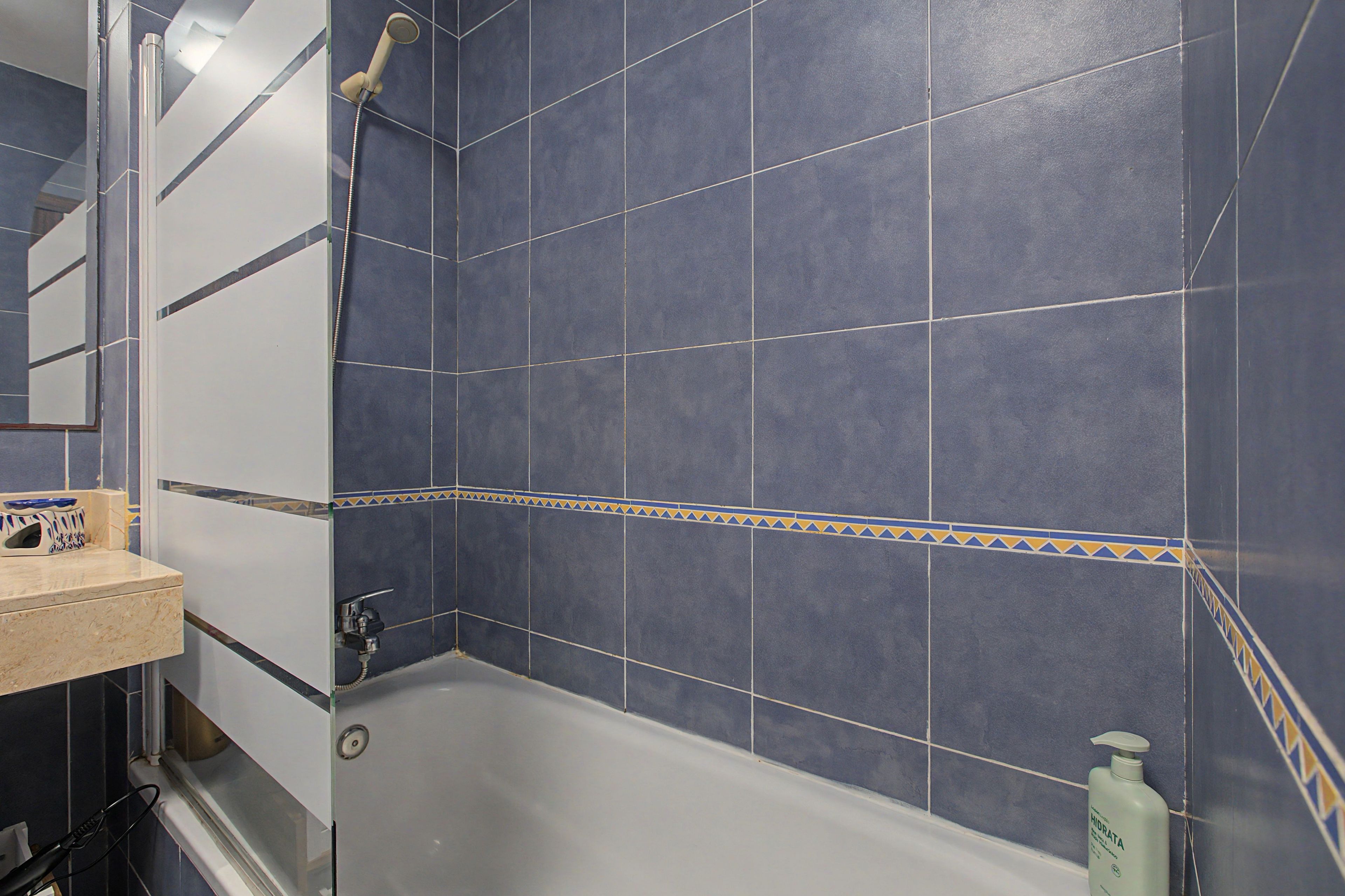 Ein Badezimmer mit einer Badewanne, einer Dusche und einem Waschbecken mit Spiegel.