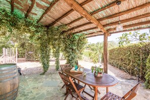 An outdoor wooden pergola with a thatched roof, surrounded by greenery and a stone patio. - Holiday Home "Independent Guesthouse in Chianti" with Pool, Garden & Wi-Fi (Castelnuovo Berardenga)