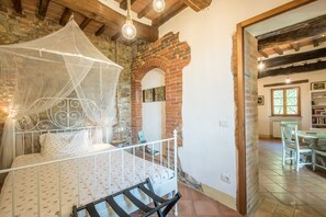 A bedroom with a bed, a white canopy, brick walls, and a wooden ceiling. - Holiday Home "Independent Guesthouse in Chianti" with Pool, Garden & Wi-Fi (Castelnuovo Berardenga)