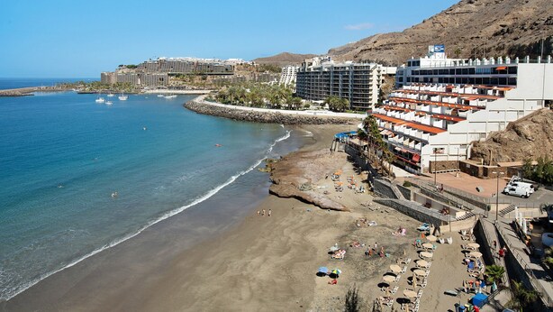 Un hôtel situé sur la côte, avec plusieurs étages, donnant sur la plage et offrant une vue sur la mer.