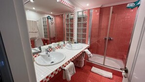 A bathroom with two sinks, a glass shower enclosure, and red-tiled walls. - Amazing Apartment with Sea View & Wi-Fi (Patalavaca-Mogán)