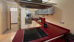 A modern kitchen with a red countertop, stainless steel appliances, and a central island. - Amazing Apartment with Sea View & Wi-Fi (Patalavaca-Mogán)