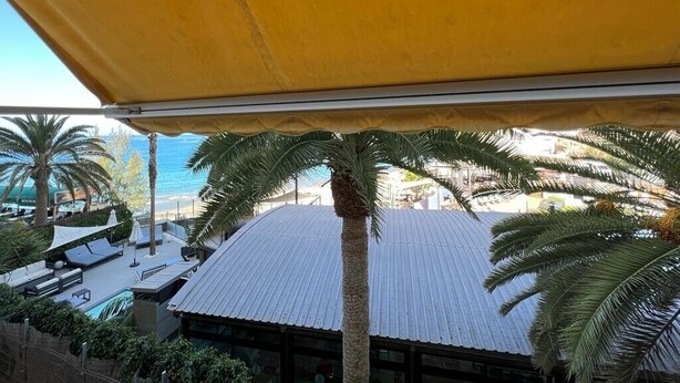 A rooftop terrace with a yellow awning, palm trees, and a view of the beach. - Amazing Apartment with Sea View & Wi-Fi (Patalavaca-Mogán)