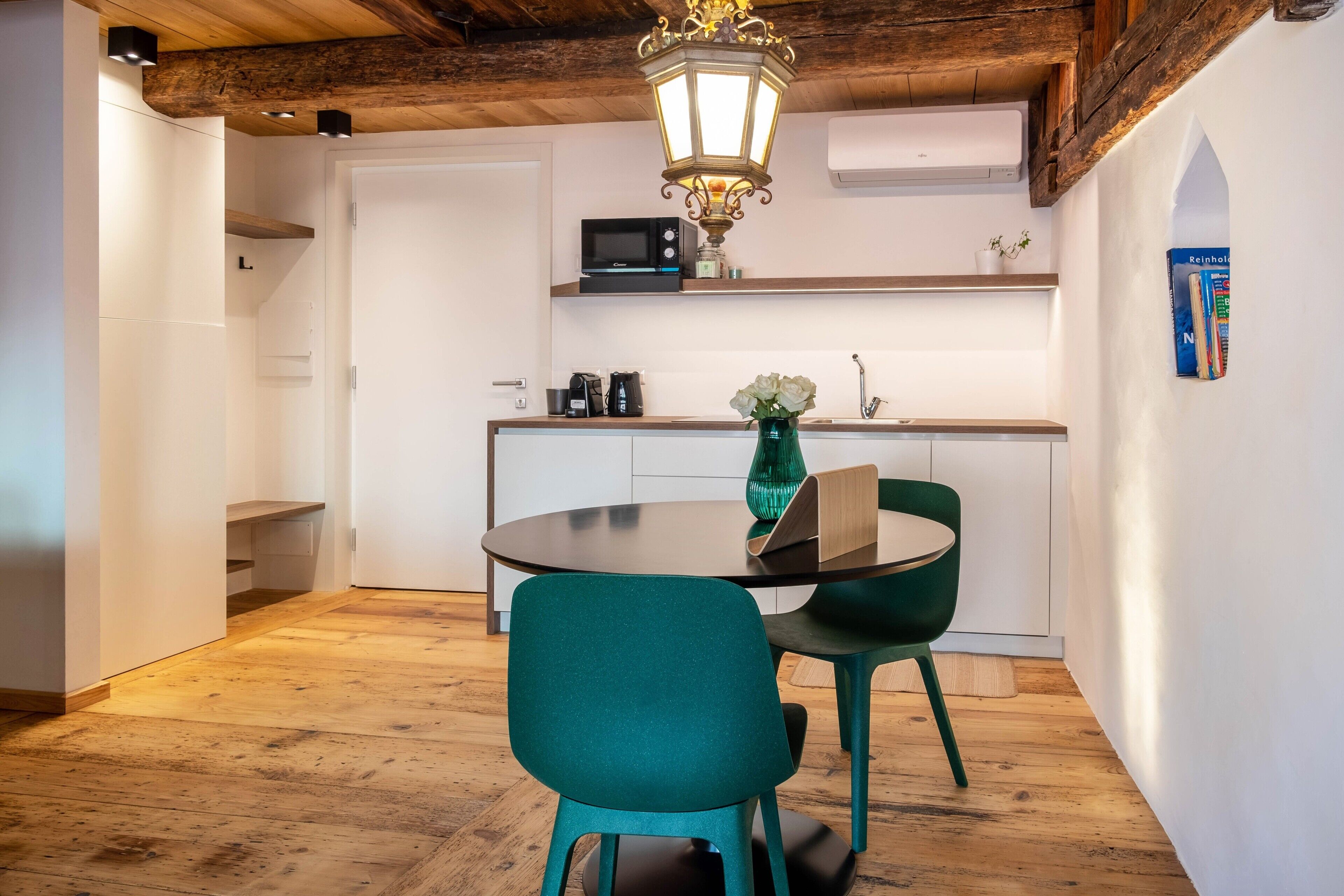 Une cuisine moderne avec un coin repas, un plancher en bois et une chaise verte.