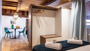 Un dormitorio con techo de madera, una cama con toallas, una mesita de noche y vistas a un comedor con sillas y una mesa.