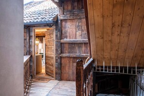 Puinen sisustus, jossa on laatoitettu katto, puinen portaikko ja ovi, joka johtaa toiseen huoneeseen.