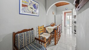 Un comedor con una mesa, sillas y un banco. Hay un cuadro en la pared y un letrero sobre la puerta.
