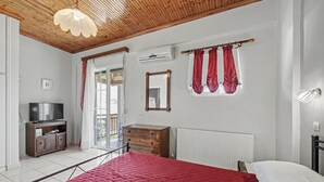 Un dormitorio con cama, cómoda, televisor y ventana con cortinas.