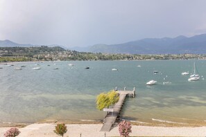 A lake with boats, a dock, and a distant shoreline with buildings and mountains. - Apartment 'Residence Gigi Complex' with Lake View, Terrace and Wi-Fi (Manerba del Garda)