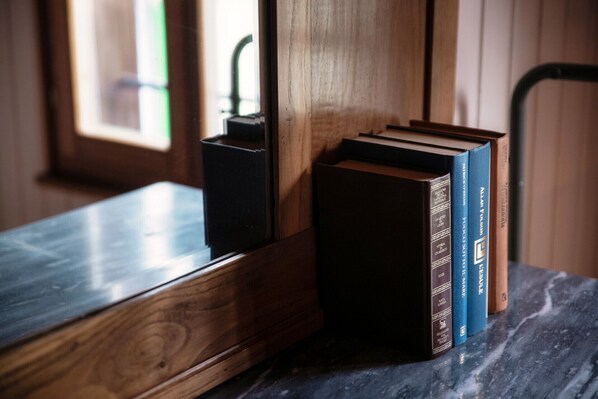 A wooden bookcase with books, a black object, and a marble table.