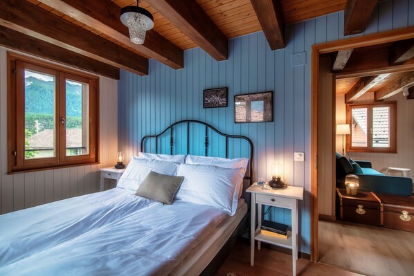 Un dormitorio con cama, mesitas de noche, cómoda y vistas al exterior.