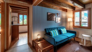 Une pièce chaleureuse avec un canapé bleu, un plafond en bois et une fenêtre donnant sur l’extérieur.