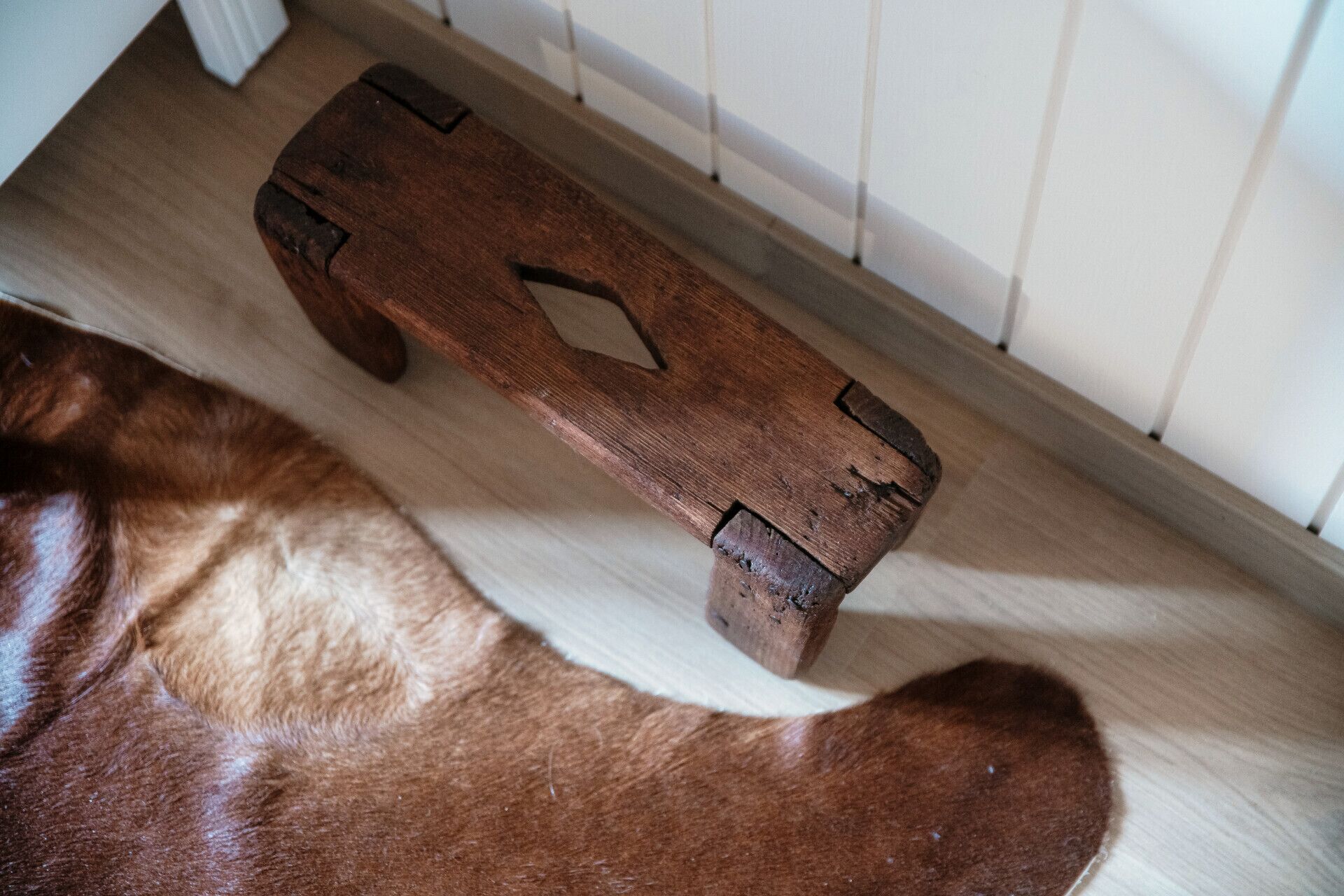A wooden bench with a simple design, placed on a light-colored floor.