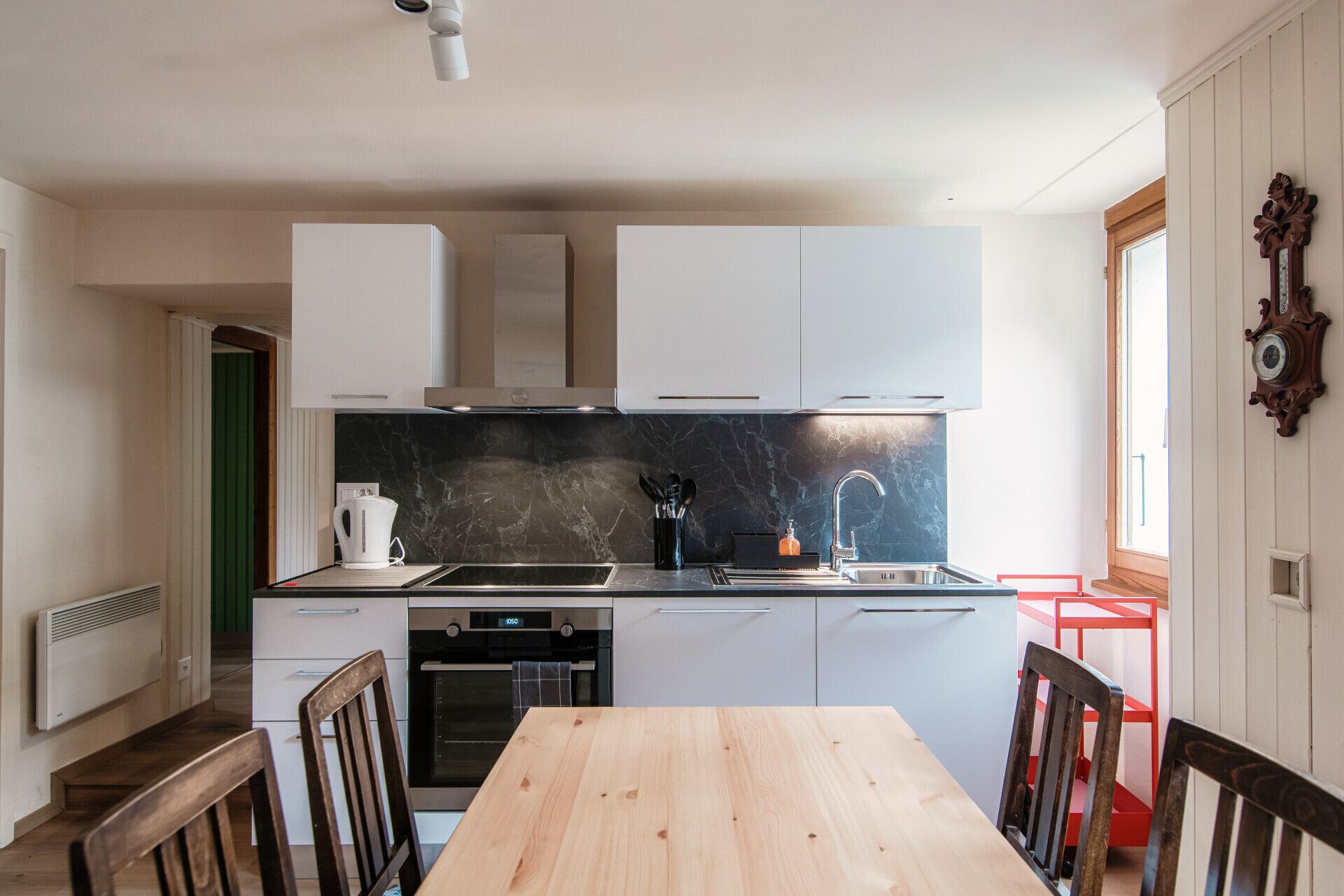 Une cuisine moderne avec des meubles blancs, un pare-feu en marbre et une table à manger en bois.