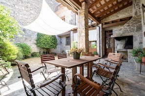 A stone building with a wooden table and chairs, a stone fireplace, and a covered outdoor area. - Apartment 'El Clos 1' with Mountain Views, Private Terrace and Wi-Fi (Conesa)