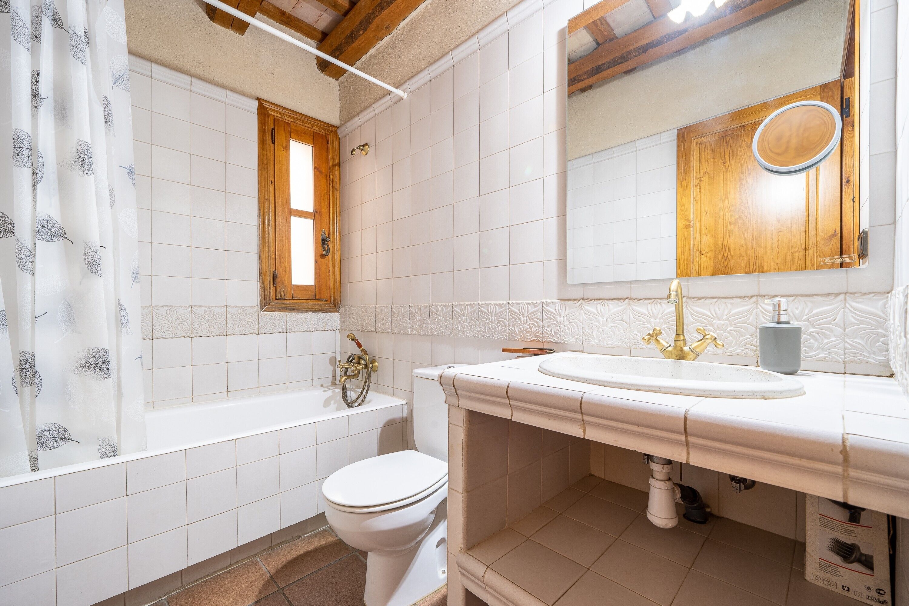 Un baño con bañera, inodoro, lavamanos y un espejo sobre él.