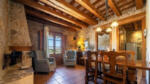 Un interior rústico con paredes de piedra, vigas de madera, una mesa de comedor y sillas.