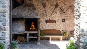 Interior de paredes de piedra con chimenea, un banco y plantas en macetas.