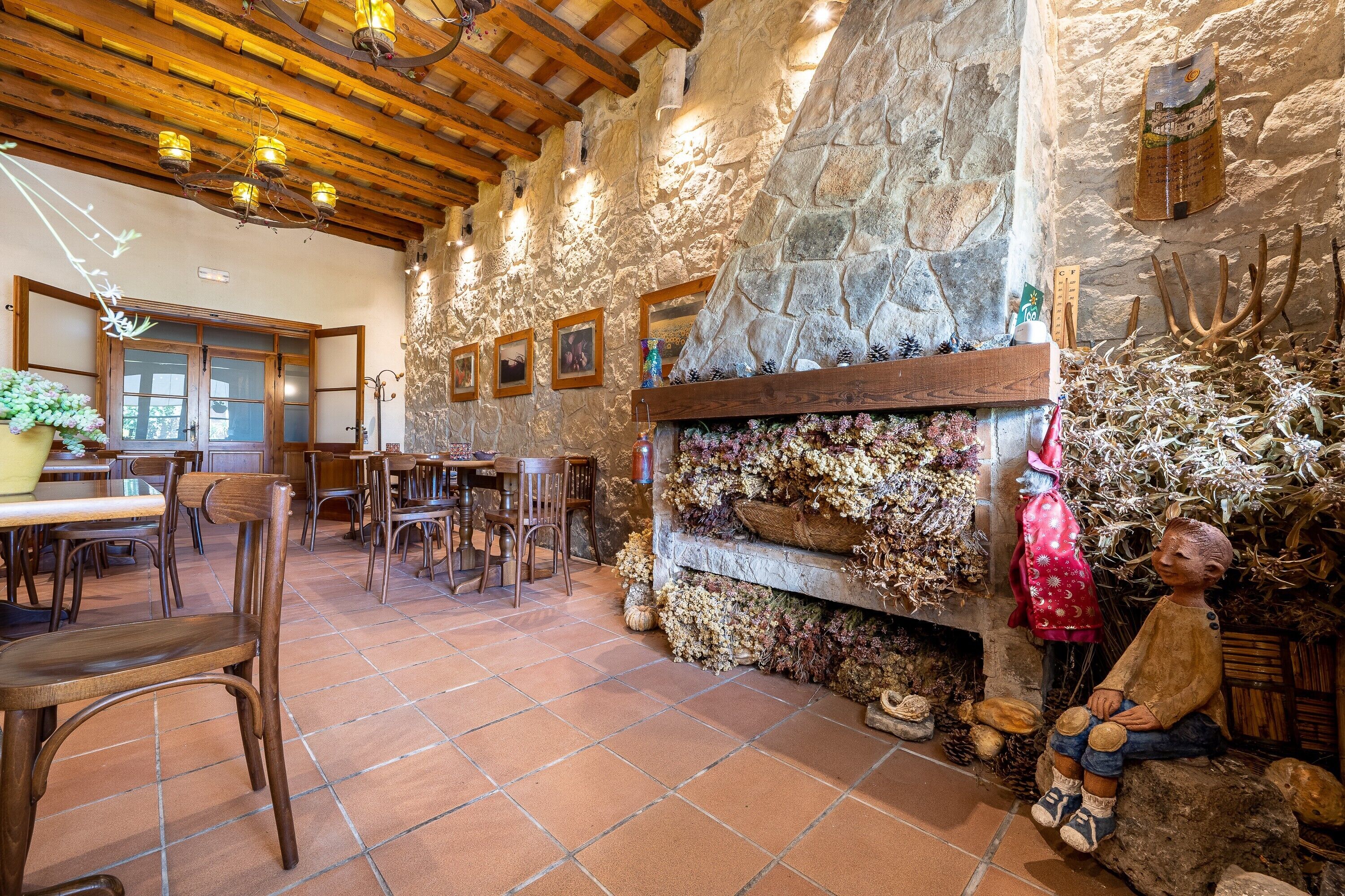 Un interior rústico con paredes de piedra, vigas de madera, chimenea y decoración campestre.