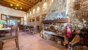 Un interior rústico con paredes de piedra, vigas de madera, chimenea y decoración campestre.