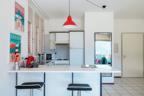 Eine moderne Küche mit einer zentralen Kochinsel, Barhocker und einer roten Pendelleuchte.