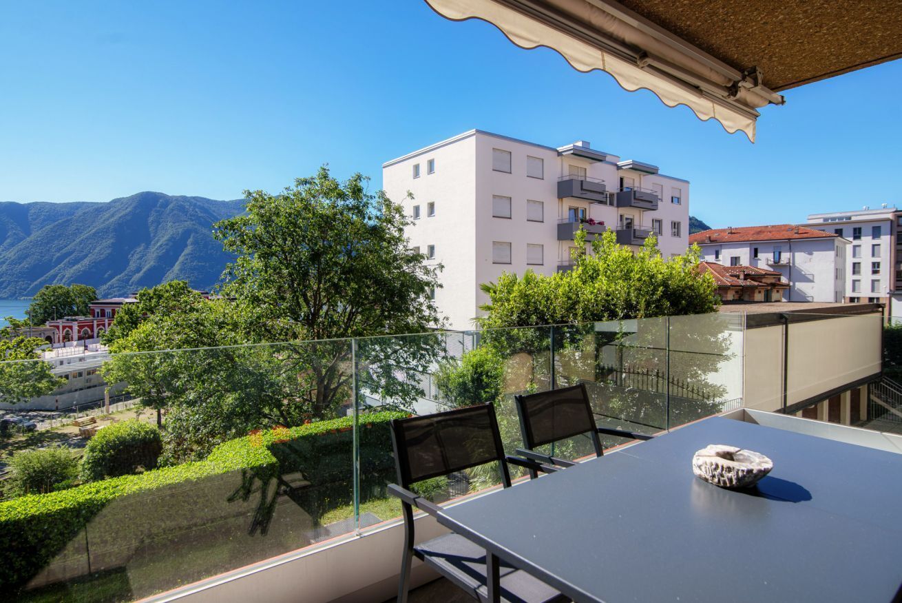 Un balcon doté d’une balustrade en verre, d’une table et de deux chaises.