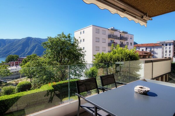 A balcony with a glass railing, a table, and two chairs.