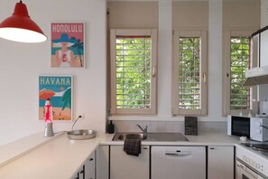 A kitchen with a white countertop, a red pendant light, a sink, and a microwave.