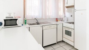A compact kitchen with a microwave, dishwasher, and stove. - Open-space apartment with lake view (PANORAMIC STUDIO) (Lugano)