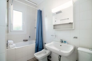 A bathroom with a bathtub, a bidet, a sink, and a toilet.