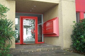 Ein Gebäudeeingang mit Glastür und einem roten Briefkasten.
