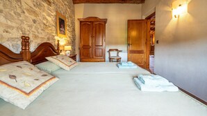 A bedroom with a stone wall, wooden bed, and a wardrobe. - Apartment 'El Clos 3' with Mountain Views, Private Terrace and Wi-Fi (CONESA)