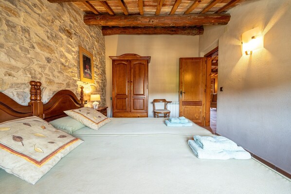 Un dormitorio con pared de piedra, cama de madera y armario.