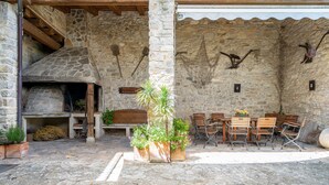 A stone building with a fireplace, outdoor seating, and decorative wall art. - Apartment 'El Clos 3' with Mountain Views, Private Terrace and Wi-Fi (CONESA)