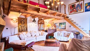 Un salon chaleureux avec un plafond en bois, un canapé blanc, un banc rouge et un escalier.