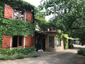 Un bâtiment rustique avec une façade en pierre, des volets en bois et des murs couverts de lierre.