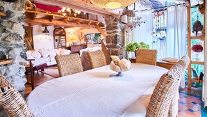 Un intérieur rustique avec des murs en pierre, des meubles en osier et une table à manger où l’on trouve du pain.