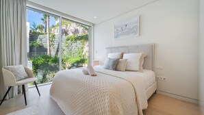 A bedroom with a large bed, a chair, a view through a sliding door, and a painting on the wall. - Palo Alto Marbella Luxury Apartment – Sea View, Wi-Fi & Air Conditioning (Ojén)