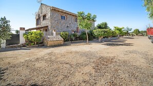 A stone building with a tiled roof, a gravel driveway, and a fenced garden area. - Holiday Home 'Casa Andrea' with Mountain Views, Shared Pool & Wi-Fi (Barbate)