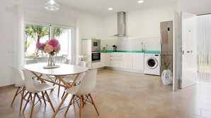 A modern kitchen with a dining area, a washing machine, and a large window.