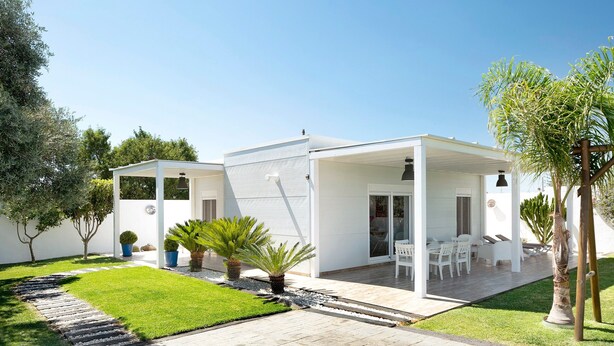 A modern house with a covered patio, a well-maintained lawn, and a stone pathway.