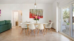 A dining area with a round table, six chairs, a vase with flowers, and a painting on the wall.