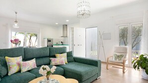 A modern living room with a green sofa, a wooden coffee table, and a butterfly pillow.
