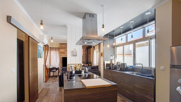 Een moderne keuken met een centraal eiland, houten kastjes en hanglampen.