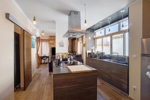 Una cocina moderna con una isla central, armarios de madera e iluminación colgante.