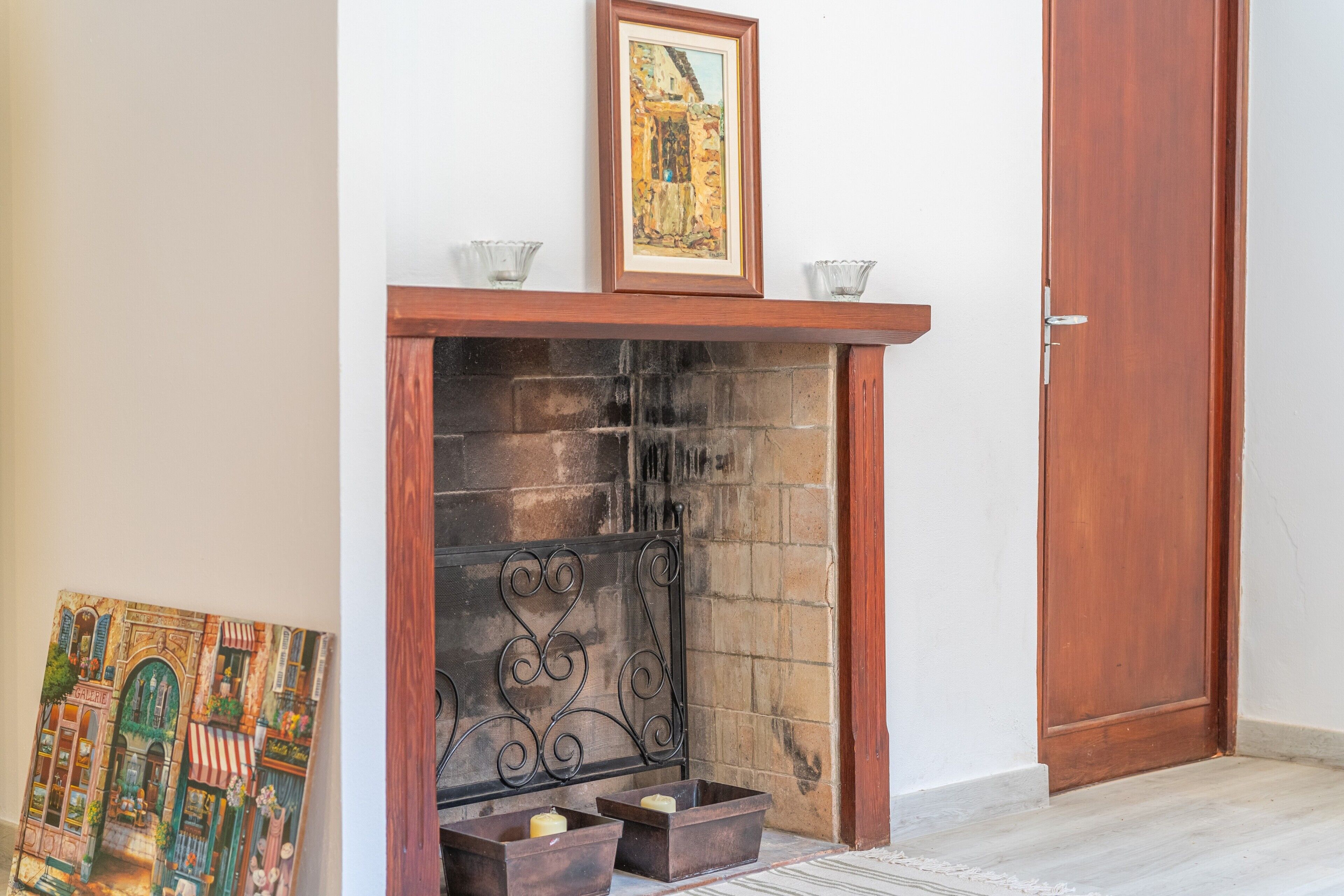 Una chimenea con repisa, una puerta y un cuadro enmarcado encima.