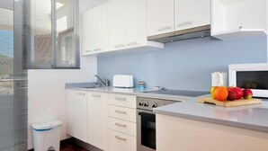 A modern kitchen with white cabinets, a microwave, a toaster, and a fruit bowl on the counter. - Vacation Home 'Tanamar' near Beach with Balcony & Wi-Fi (Puerto Pollensa)