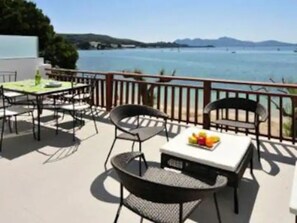 A terrace with outdoor seating, a table with a fruit bowl, and a view of the sea and hills. - 'Apartment Rafael' with Sea View, Terrace & Wi-Fi (Port de Pollença)